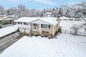 Split foyer home with brick siding, driveway, and a chimney