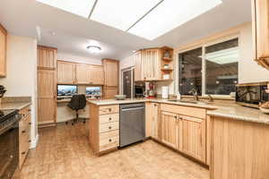 Kitchen with a sink, stainless steel dishwasher, and light brown cabinetry