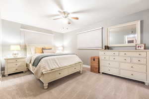 Bedroom with light carpet, a ceiling fan, and baseboards