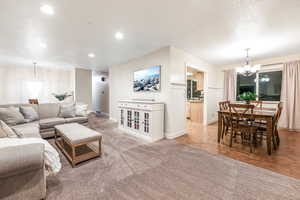 Living room with recessed lighting, light colored carpet, a textured ceiling, a chandelier, and baseboards