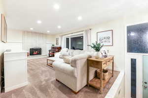 Living room featuring a brick fireplace, recessed lighting, and light colored carpet