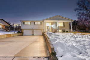 View of front of property featuring an attached garage, concrete driveway, brick siding, and a porch