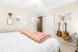 Carpeted bedroom featuring a ceiling fan and a closet