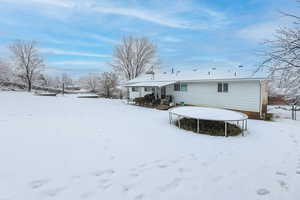 Snow covered house featuring a trampoline and fence