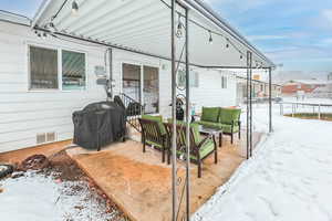 Snow covered patio featuring a trampoline, visible vents, outdoor lounge area, a grill, and fence