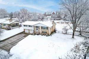 Bi-level home featuring driveway, a garage, a residential view, and a chimney