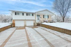 Split foyer home with a garage, concrete driveway, and brick siding