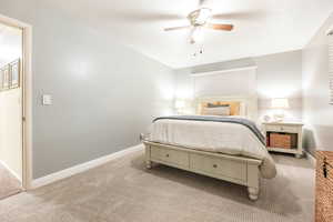 Bedroom with a ceiling fan, light carpet, and baseboards