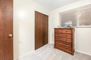 Bedroom featuring baseboards, a closet, and light colored carpet