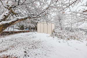 Snowy yard with a storage shed and an outdoor structure