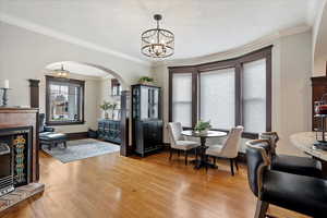 Dining room with an inviting chandelier, arched walkways, and light wood-style floors