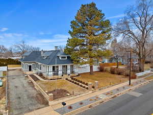 View of front of house with a chimney, a porch, a front yard, fence private yard, and driveway