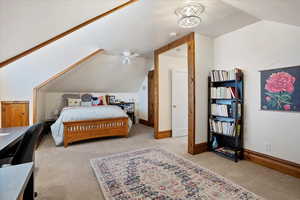 Bedroom featuring light colored carpet, vaulted ceiling, a textured ceiling, and baseboards