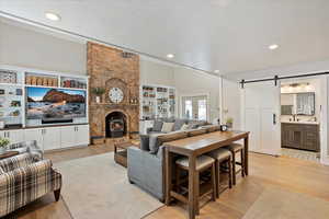 Family room area with a wood stove, light wood-style floors, a barn door, and french doors