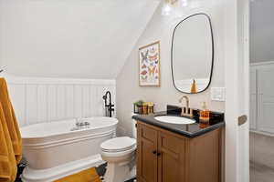 Full bathroom featuring a freestanding bath, vaulted ceiling, vanity, and toilet