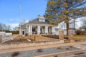 View of front of house with metal roof, a fenced front yard, covered porch, roof with shingles, and a chimney