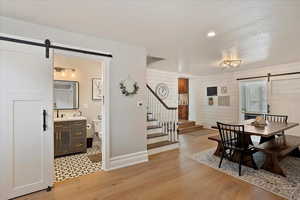 Dining space featuring stairs, a textured ceiling, light wood finished floors, and a barn door