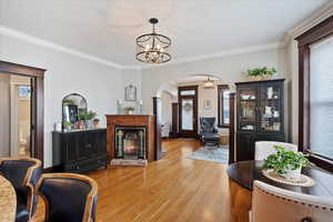 Interior space with arched walkways, wood finished floors, a lit fireplace, plenty of natural light, and an inviting chandelier