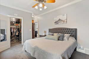 Carpeted bedroom featuring crown molding, a closet, visible vents, a spacious closet, and baseboards