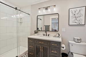 Bathroom featuring toilet, a stall shower, and vanity