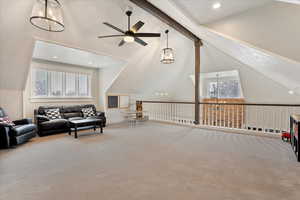 Carpeted living room with ceiling fan, high vaulted ceiling, beamed ceiling, and plenty of natural light