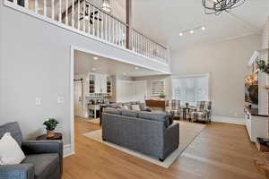 Family room area with baseboards, recessed lighting, a towering ceiling, and light wood-style floors