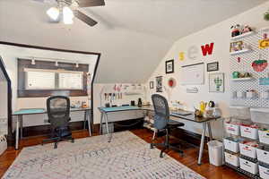 Office area featuring dark wood-style flooring, a ceiling fan, vaulted ceiling, a textured ceiling, and baseboards