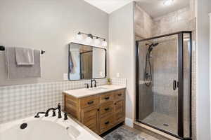 Full bathroom featuring a stall shower, a garden tub, and vanity