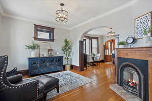 Living area featuring plenty of natural light, arched walkways, wood finished floors, and a glass covered fireplace