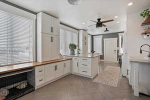 Laundry/ mudroom  featuring a peninsula, open shelves, a sink, and white cabinets