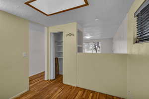 Unfurnished room with a textured ceiling, wood finished floors, and baseboards