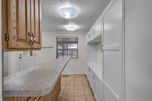 Mudroom with a textured ceiling, light tile patterned flooring, visible vents, and baseboards