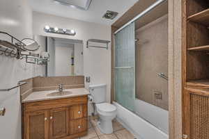 Bathroom featuring visible vents, bath / shower combo with glass door, toilet, tile patterned flooring, and vanity