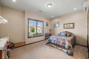 Bedroom with baseboards, visible vents, an AC wall unit, carpet flooring, and recessed lighting