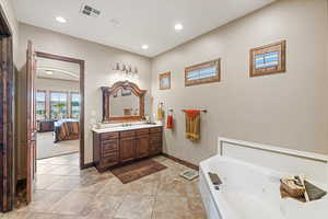 Ensuite bathroom with vanity, visible vents, baseboards, a tub with jets, and ensuite bath