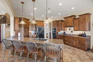 Kitchen with dark stone counters, black appliances, visible vents, and decorative light fixtures