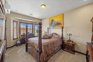 Bedroom with baseboards, a wall mounted air conditioner, visible vents, and light colored carpet