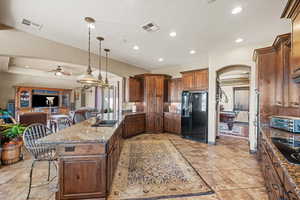 Kitchen featuring a breakfast bar area, a sink, open floor plan, hanging light fixtures, and black appliances