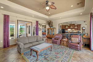 Living area featuring arched walkways, a raised ceiling, visible vents, and recessed lighting