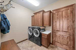 Washroom with washer and clothes dryer, cabinet space, and baseboards