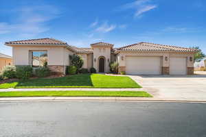 Mediterranean / spanish-style home featuring stucco siding, concrete driveway, an attached garage, stone siding, and a front lawn