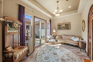 Living area with stone finish flooring, a tray ceiling, and a notable chandelier