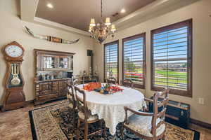 Dining space featuring baseboards, a raised ceiling, a notable chandelier, and recessed lighting