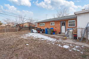 Back of house featuring entry steps, brick siding, and fence