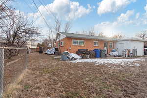 Rear view of property with central AC, brick siding, and fence