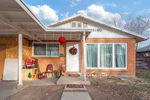 View of front of house with a patio and brick siding