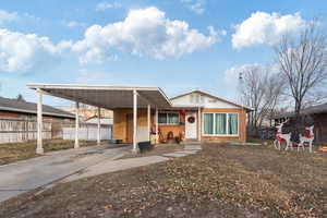 View of front of property with driveway, fence, an attached carport, and brick siding