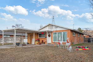 Bungalow-style house featuring brick siding, concrete driveway, a front yard, fence, and an attached carport