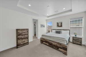 Bedroom featuring light carpet, recessed lighting, a raised ceiling, and baseboards