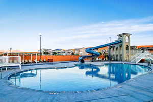 Pool with a residential view, a water slide, and fence